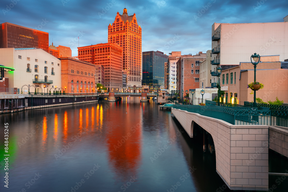Milwaukee, Wisconsin, USA. Cityscape image of downtown Milwaukee, Wisconsin, USA with reflection of the skyline in Milwaukee River at summer sunset.
