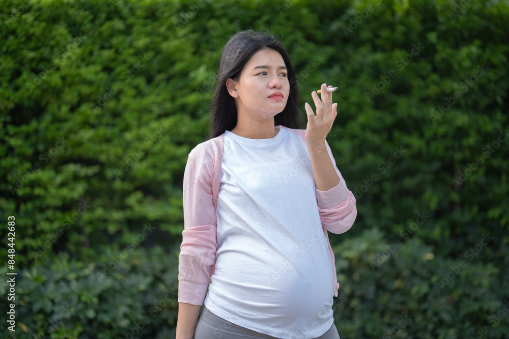 A Portrait of Asian pregnant woman smoking cigarette. Having a baby. Family people lifestyle. Mom love. A Portrait of Asian pregnant woman smoking cigarette. Having a baby. Family people lifestyle. Mom love.