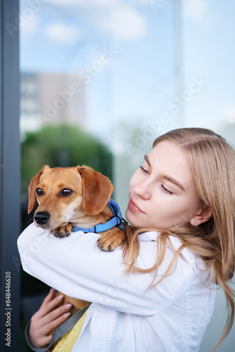 Young veterinarian smiling and holding dog near the vet clinic entrance. Healthy dog, diagnostic, treatment of domestic animals. High quality photo © boytsov