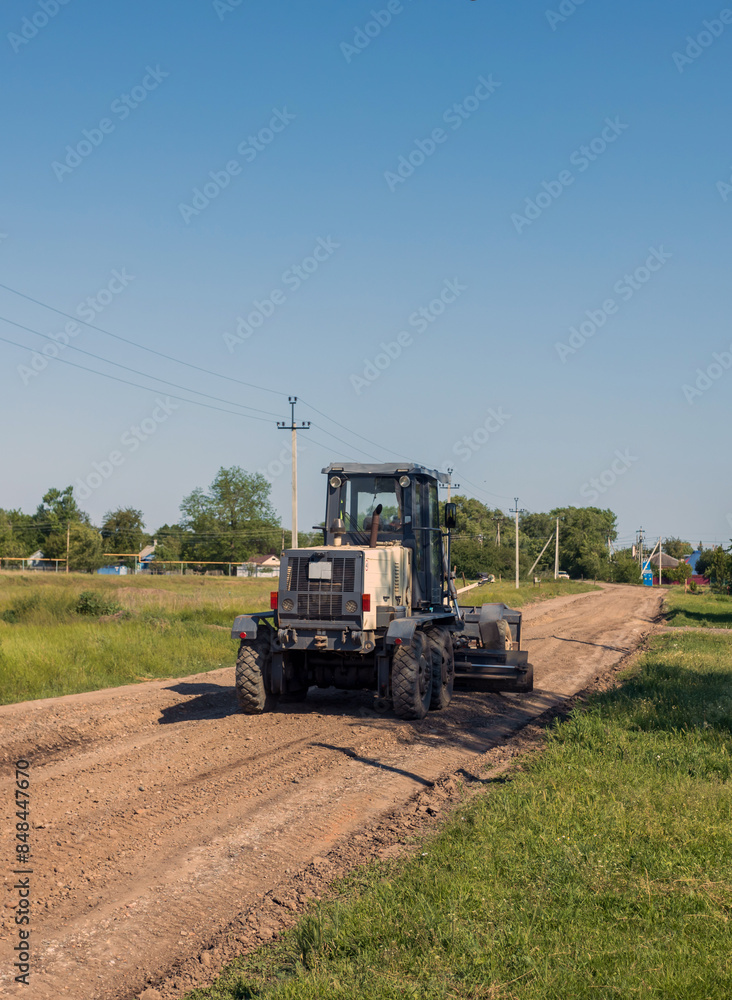 a motor grader levels the surface of a rural road, a road machine at road construction a motor grader levels the surface of a rural road, a road machine at road construction