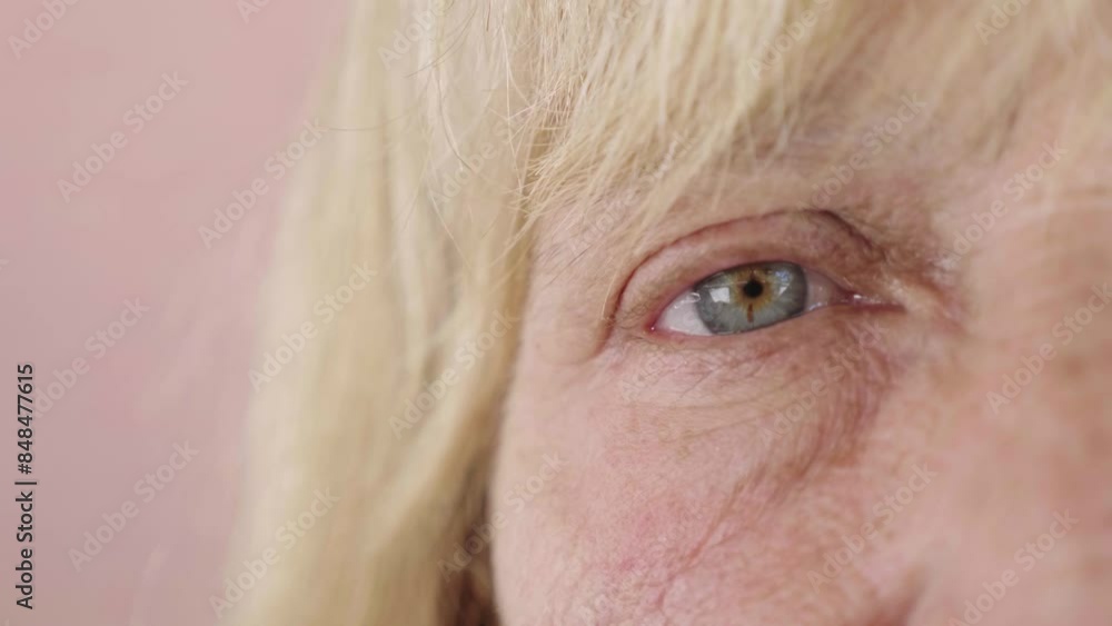 Close-up shot of a mature blonde woman's single blue/green eye, highlighting the intricate details of her iris. Close-up shot of a mature blonde woman's single blue/green eye, highlighting the intricate details of her iris.