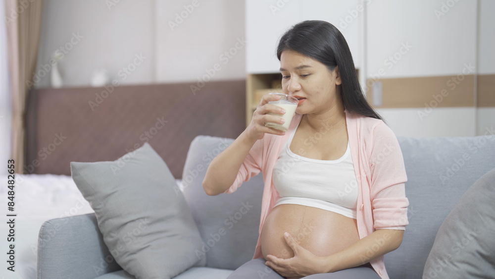 A portrait of happy Asian pregnant woman drinking milk for calcium in bedroom at home. Having a baby. Family people lifestyle. Mom love. A portrait of happy Asian pregnant woman drinking milk for calcium in bedroom at home. Having a baby. Family people lifestyle. Mom love.