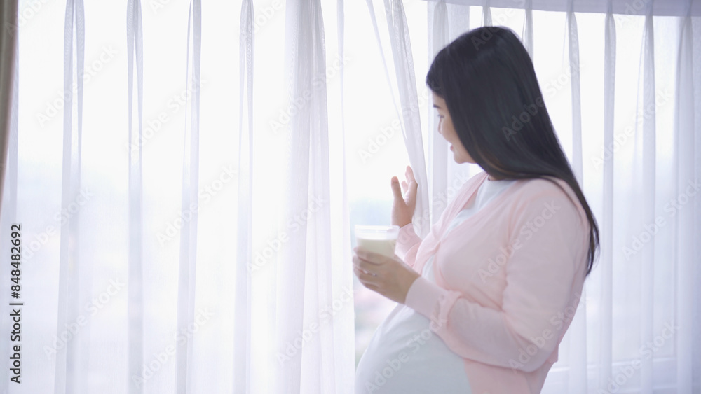 A portrait of happy Asian pregnant woman drinking milk for calcium in bedroom at home. Having a baby. Family people lifestyle. Mom love. A portrait of happy Asian pregnant woman drinking milk for calcium in bedroom at home. Having a baby. Family people lifestyle. Mom love.