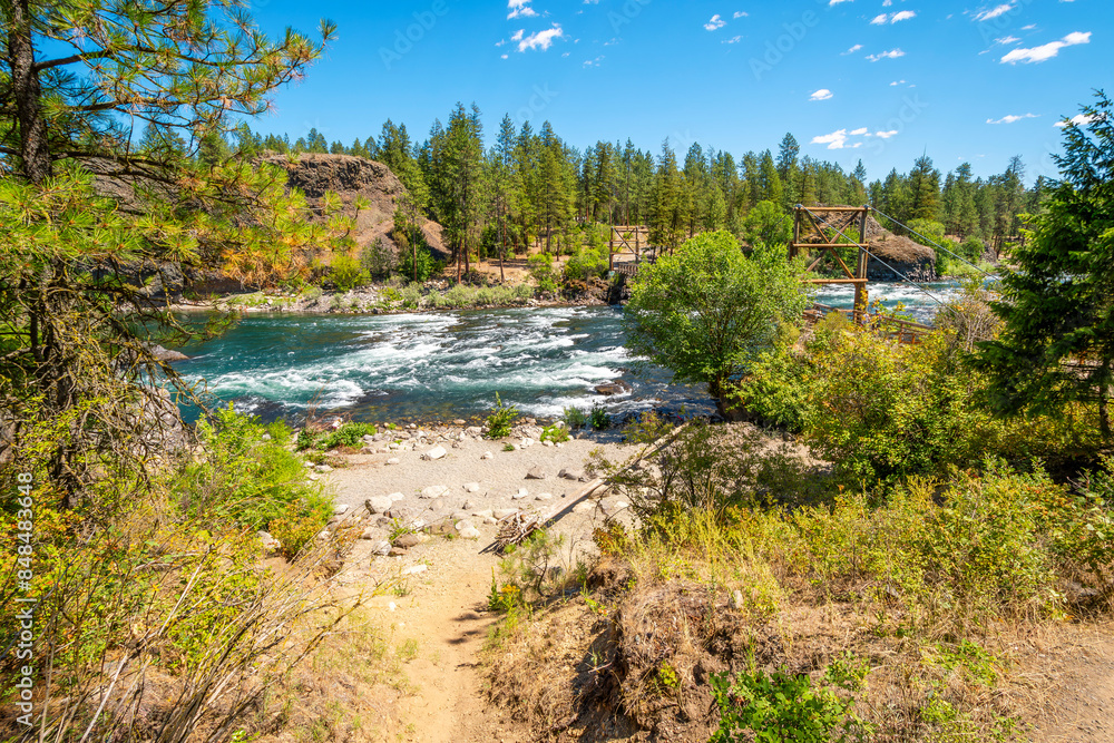 A small sandy beach along the rapids of the Spokane River as it runs under the wooden suspension bridge at the Bowl and Pitcher area of Riverside State Park in Spokane, Washington, USA A small sandy beach along the rapids of the Spokane River as it runs under the wooden suspension bridge at the Bowl and Pitcher area of Riverside State Park in Spokane, Washington, USA