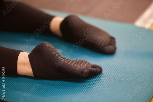 Person in grey sportswear exercising on yoga mat with suspension strap photo