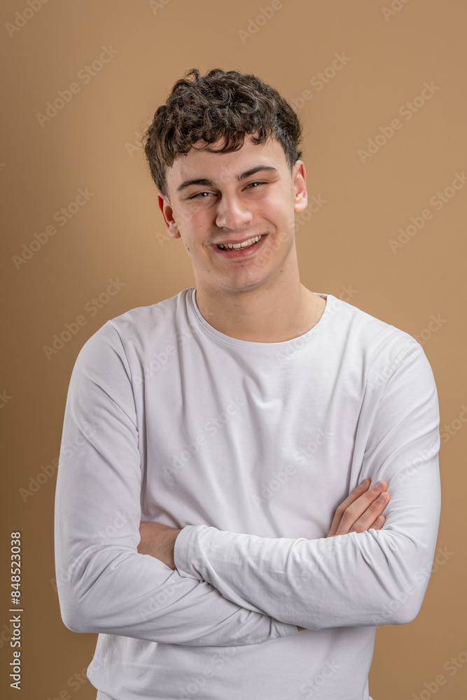 Portrait of one caucasian man 20 years old looking to the camera in front of almond color studio background smiling wearing casual shirt copy space Portrait of one caucasian man 20 years old looking to the camera in front of almond color studio background smiling wearing casual shirt copy space