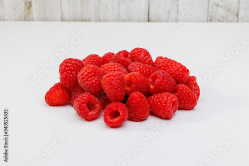 Red Raspberries Piled on White Countertop with White Wooden Background