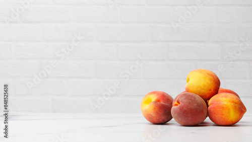 Five Peaches Stack on White Countertop with White Brick Backdrop