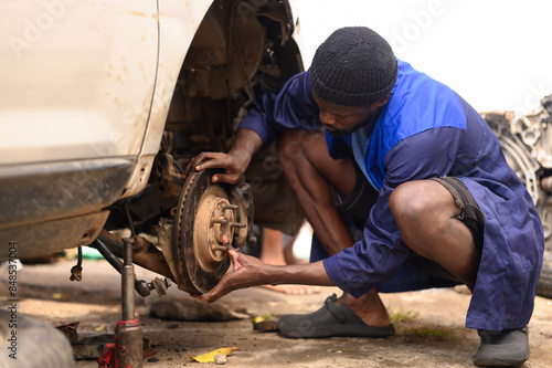 Car Mechanic checking and maintaining a car brake pad. 