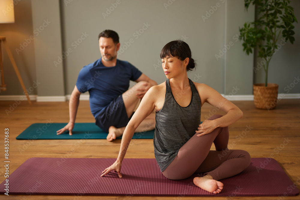 Caucasian man and Asian woman practicing yoga together in yoga studio Caucasian man and Asian woman practicing yoga together in yoga studio