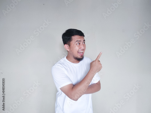 Mature Asian man with a happy expression while pointing to the empty area beside him photo