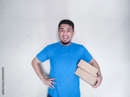 Adult Asian man smiling happy while delivering a package cardbox photo