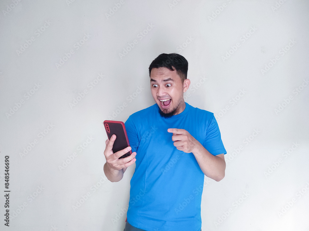 Asian mature man smiling while holding his cell phone and pointing at it Asian mature man smiling while holding his cell phone and pointing at it