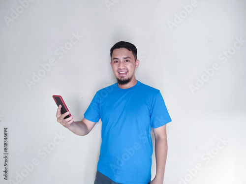 Adult Asian man smiling happy while holding a cellular phone photo