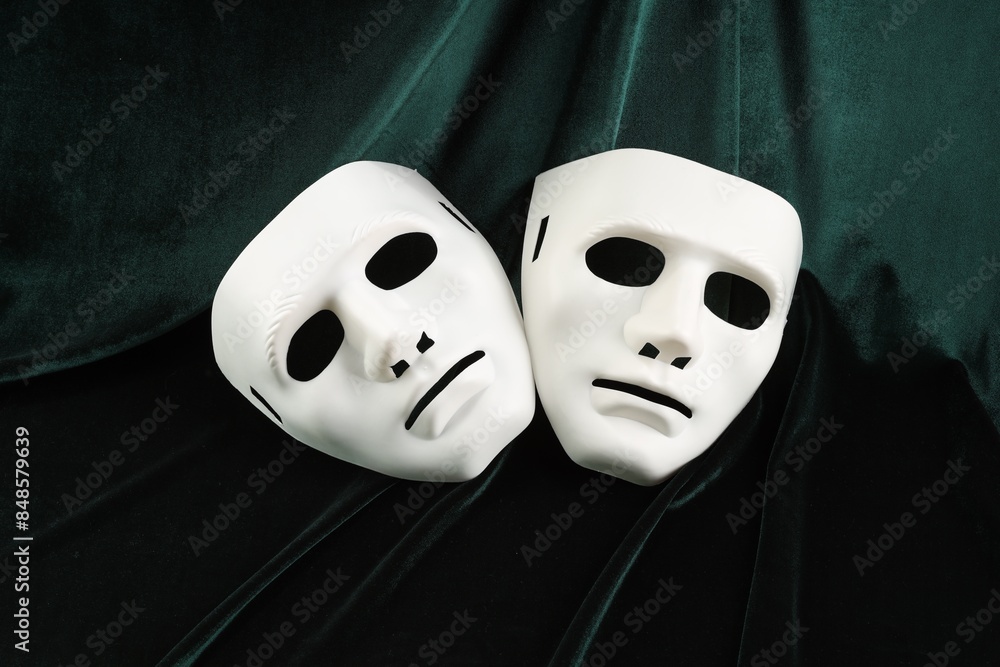 Theater arts. White masks on green fabric Theater arts. White masks on green fabric