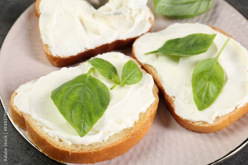 Delicious sandwiches with cream cheese and basil leaves on grey table, closeup Delicious sandwiches with cream cheese and basil leaves on grey table, closeup