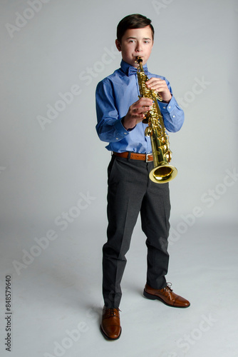 Well dressed young male standing playing a soprano saxophone with expert skill 