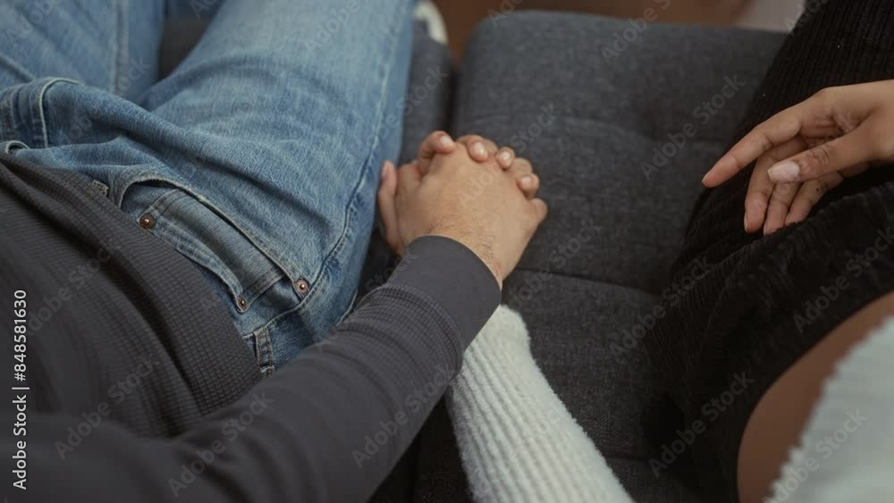 Intimate moment of a man and woman holding hands on a sofa, symbolizing love and togetherness in a cozy home setting. Intimate moment of a man and woman holding hands on a sofa, symbolizing love and togetherness in a cozy home setting.