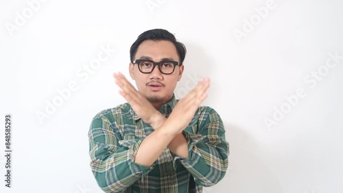 Footage of smillling young Asian man wearing plaid shirt showing stop palm gesture refusing. photo