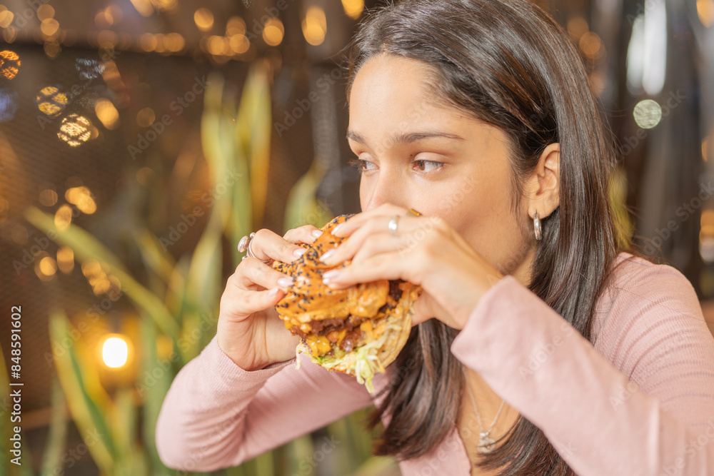 Woman enjoying her hamburger in the restaurant Woman enjoying her hamburger in the restaurant