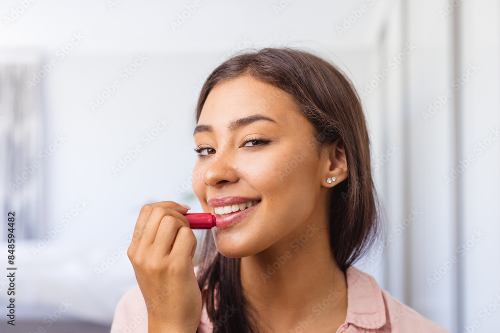 Happy biracial woman applying lipstick, smiling confidently Happy biracial woman applying lipstick, smiling confidently