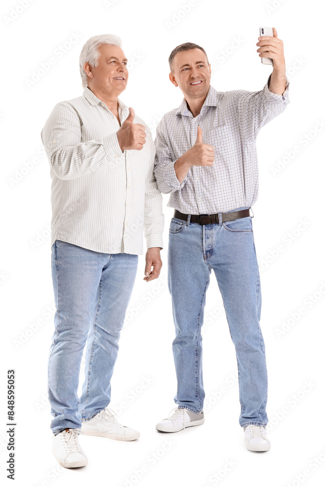 Mature brothers with mobile phone taking selfie on white background Mature brothers with mobile phone taking selfie on white background