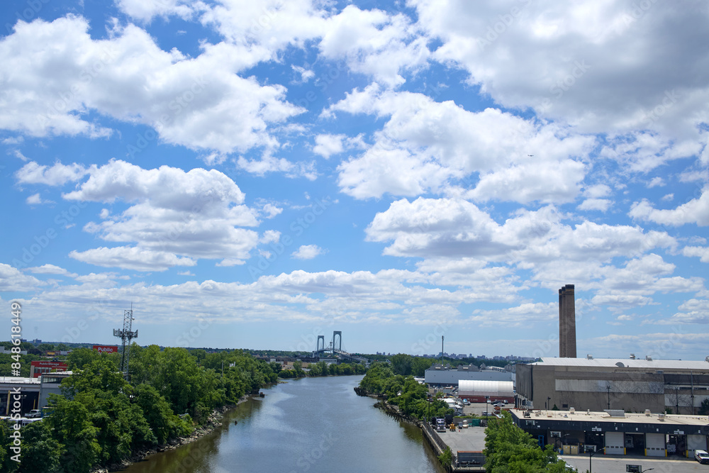 Fototapeta premium Bright blue sky with soft fluffy clouds. Building in the distance.