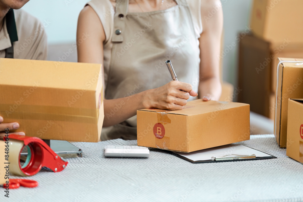 E-Business Concept: Entrepreneurs Packaging Products for Online Shipping and Delivery in a Modern Workspace E-Business Concept: Entrepreneurs Packaging Products for Online Shipping and Delivery in a Modern Workspace