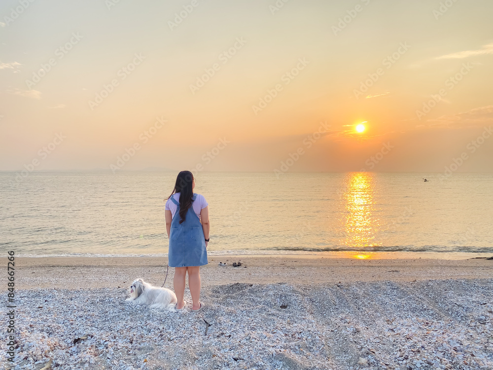 Young asian woman with her dog enjoying and relaxing on the seaside during sunset. Young asian woman with her dog enjoying and relaxing on the seaside during sunset.
