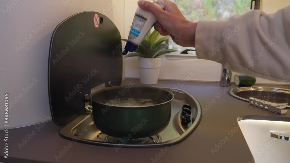 Adding salt to boiling pot for making mashed potatoes in camper kitchen Adding salt to boiling pot for making mashed potatoes in camper kitchen
