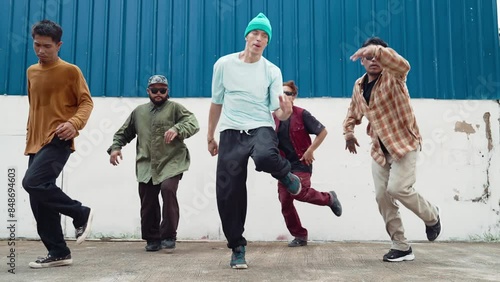Group of hip hop choreographer dancing street dance together at wall. Young handsome dancer team practicing break dance, move to modern rhythm, express feeling of lively. Outdoor sport 2024. hiphop.