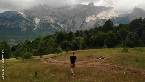 Drone video of a tourist walking in front of mountain ranges of the Tet National Park in the Albania photo