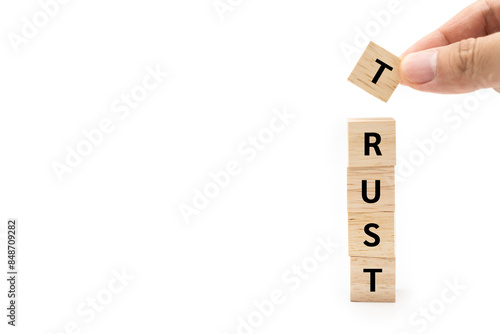 Hand putting wood cube block with TRUST text isolated on white background. Brand building for success concept. Building trust business concept. photo