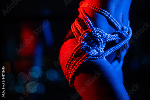 Close-up of a woman's belly in ropes tied using the Japanese shibari technique.  photo