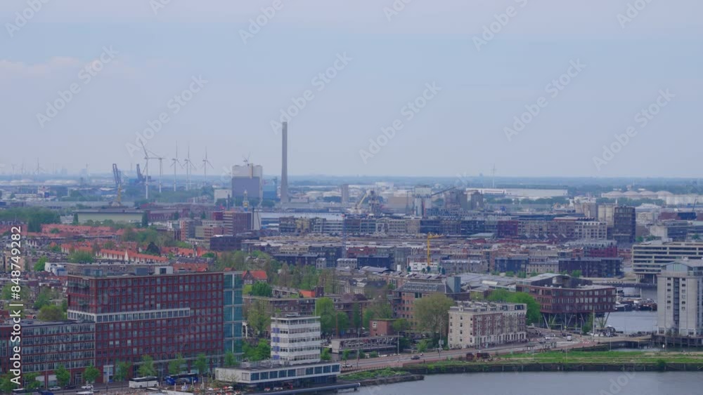 Aerial view of Amsterdam with commercial, industrial and residential buildings, with several wind turbines in the distance, on a hazy spring day Aerial view of Amsterdam with commercial, industrial and residential buildings, with several wind turbines in the distance, on a hazy spring day