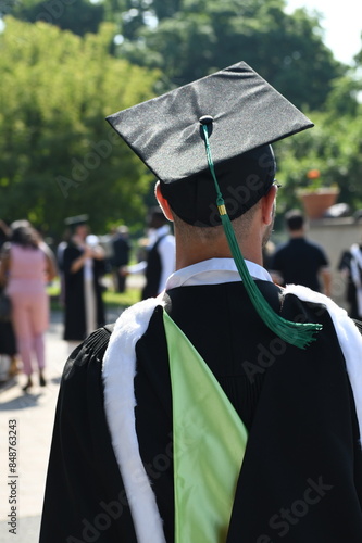 Rear view of university graduate wearing graduation gown and cap in the commencement day.