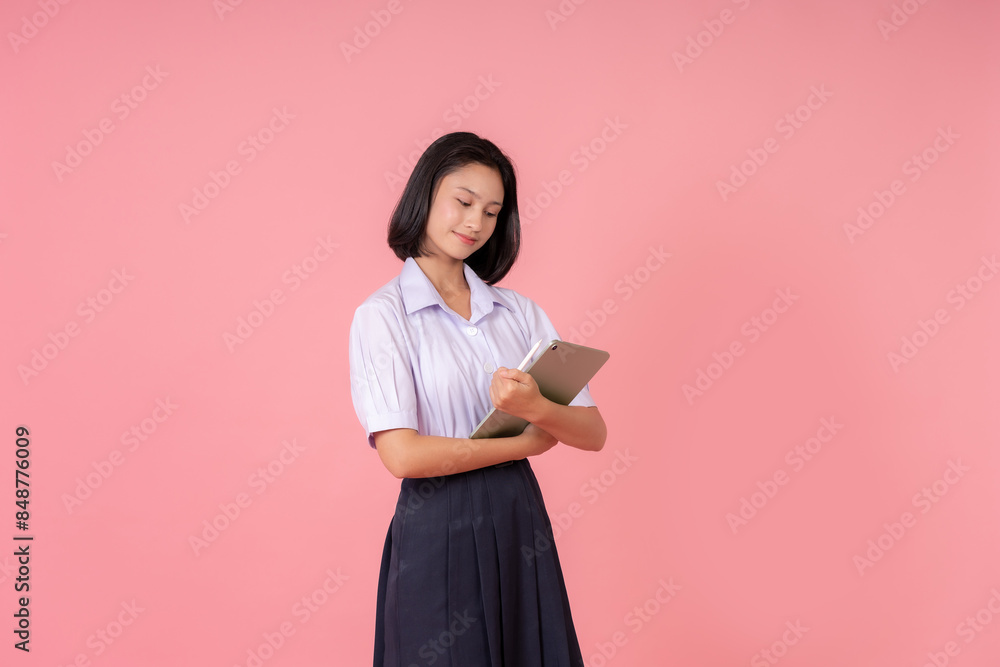 half body photo of Asian female high school students Holding a laptop for online study, preparing for midterm exams, and posing for a photo in a studio with a pink background. half body photo of Asian female high school students Holding a laptop for online study, preparing for midterm exams, and posing for a photo in a studio with a pink background.