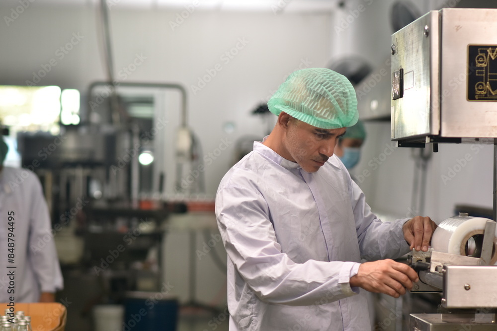 Obraz premium Worker in food factory chceking machine for packing product.