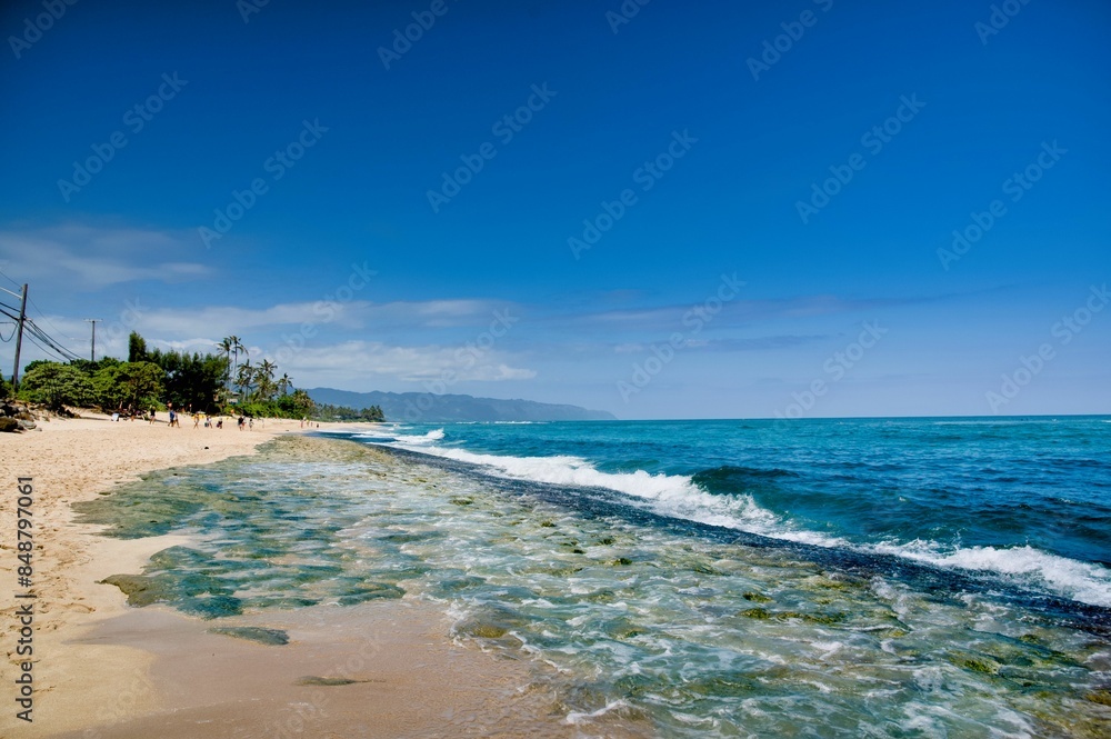 Fototapeta premium Beautiful beach with clear blue water and a bright sky on a sunny day