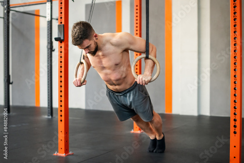 Fotografie Fit male gymnast doing calisthenics ring push up exercise