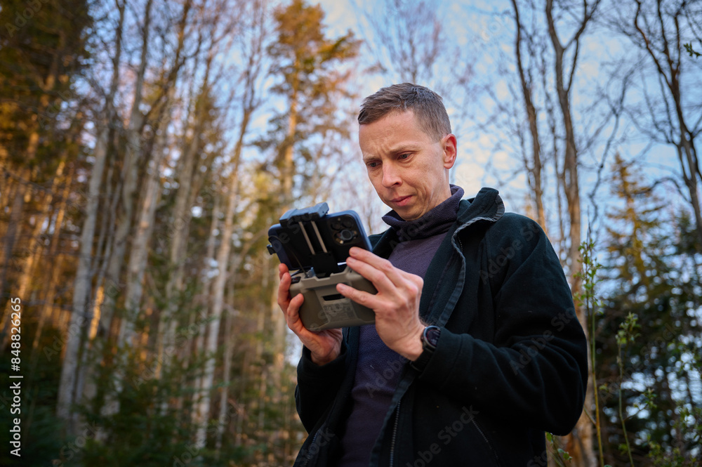 Close up view of drone operator holding remote controller in the mountains. Traveler controlling a drone flying over mountains with remote control. Shooting aerial videography and photography. Close up view of drone operator holding remote controller in the mountains. Traveler controlling a drone flying over mountains with remote control. Shooting aerial videography and photography.