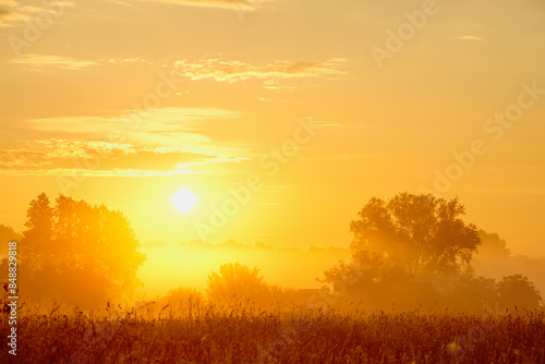 Sunrise on a foggy summer morning over the countryside
