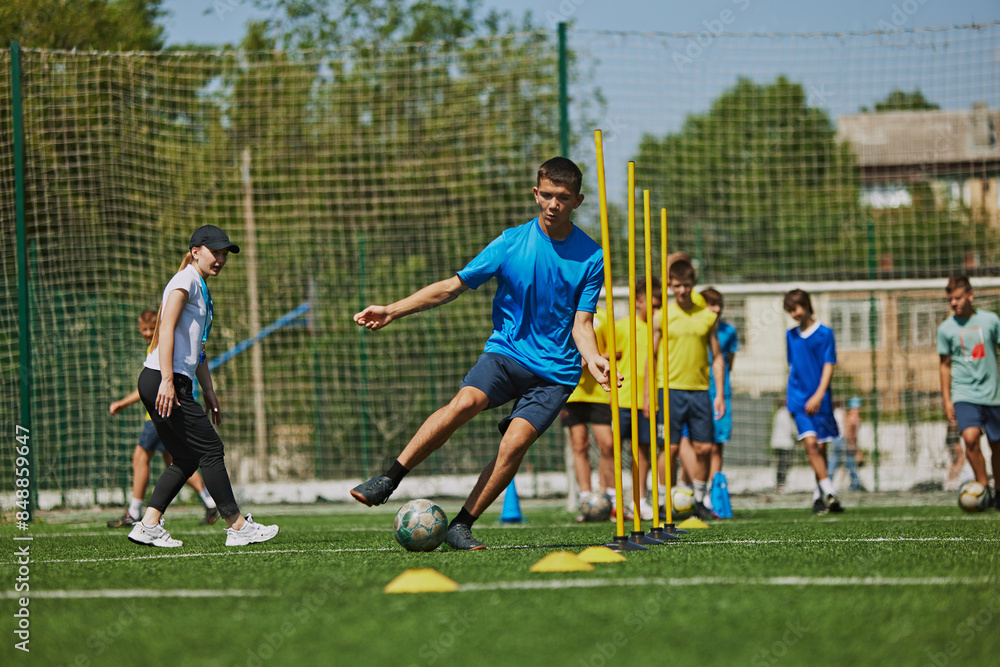 Obraz premium Teamwork and Agility. Young soccer players in uniforms raining outdoors on football field with coach, growing skills and endurance. Concept of sport, school, childhood, hobby, active lifestyle