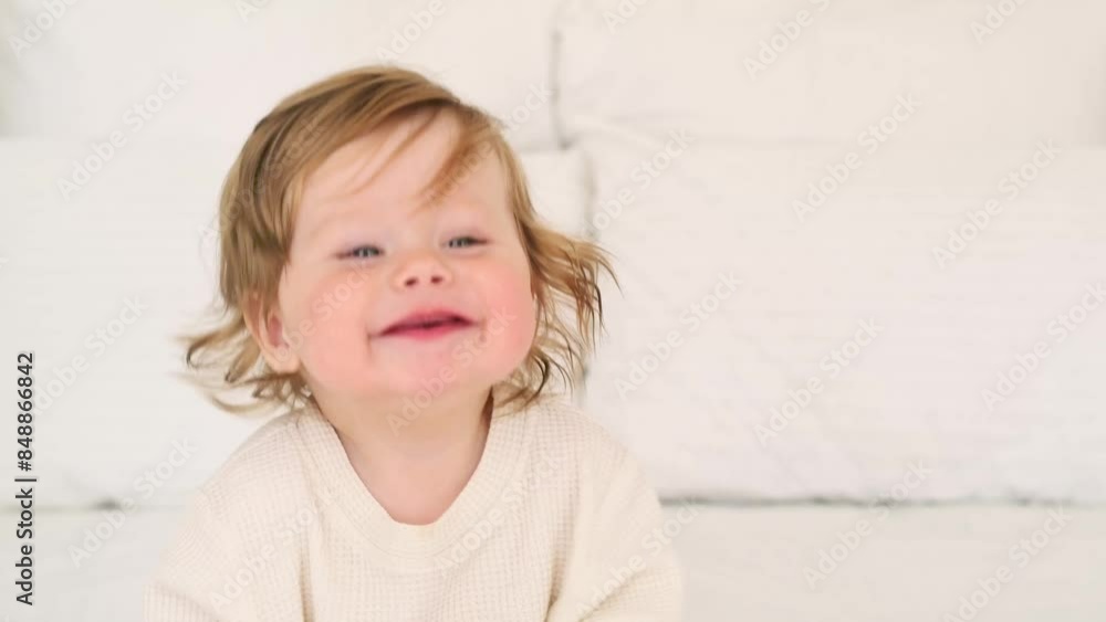 A joyful baby with red hair and blue eyes in a white bodysuit on the bed at home laughing, healthy happy cute newborn baby boy close-up A joyful baby with red hair and blue eyes in a white bodysuit on the bed at home laughing, healthy happy cute newborn baby boy close-up