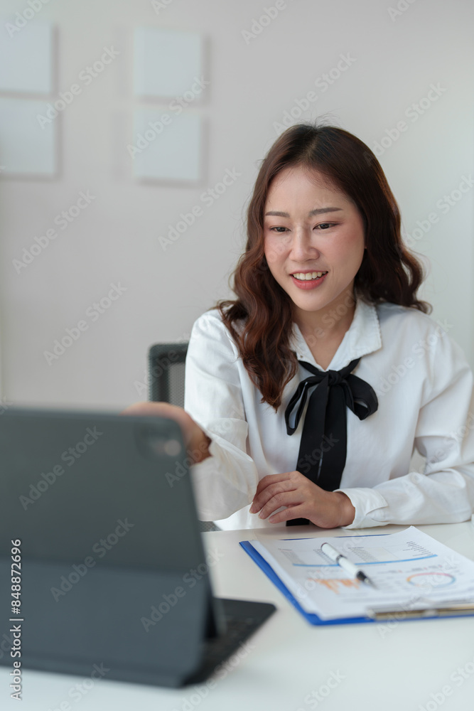 Asian female freelancer sitting and working with laptop doing paperwork, calculations, recording business information online at your desk in your home office. Success concept modern entrepreneur. Asian female freelancer sitting and working with laptop doing paperwork, calculations, recording business information online at your desk in your home office. Success concept modern entrepreneur.