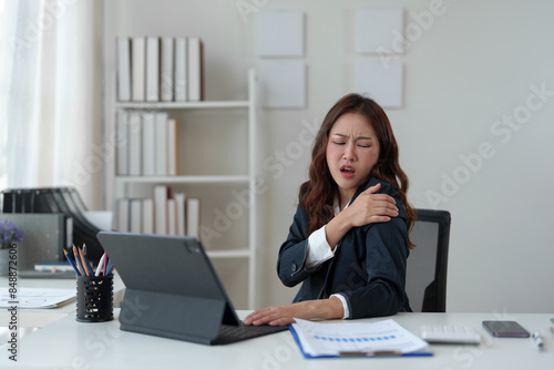 Tired businesswoman having a headache in modern office Creative woman working at a desk Ordinary female office worker Feel body aches while working hard on your laptop computer.