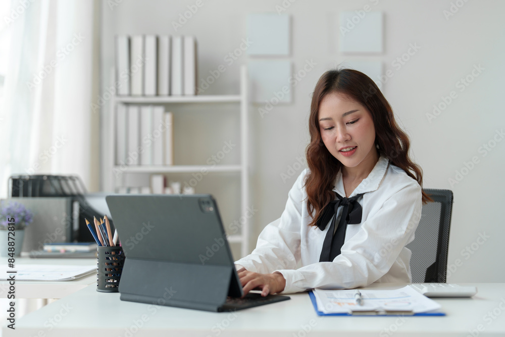 Asian female freelancer sitting and working with laptop doing paperwork, calculations, recording business information online at your desk in your home office. Success concept modern entrepreneur. Asian female freelancer sitting and working with laptop doing paperwork, calculations, recording business information online at your desk in your home office. Success concept modern entrepreneur.