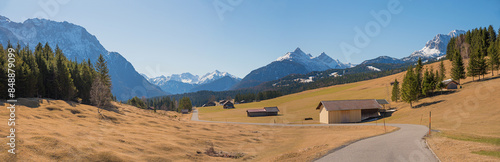 country road in idyllic landscape upper bavaria, with wooden huts, view to karwendel alps. Buckelwiesen. photo