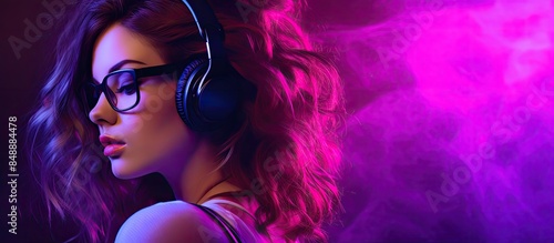 Teen hipster girl in stylish glasses and headphones listens to trance music mix in trendy 80s 90s nightclub lighting Her profile is against a purple studio background with copy space image