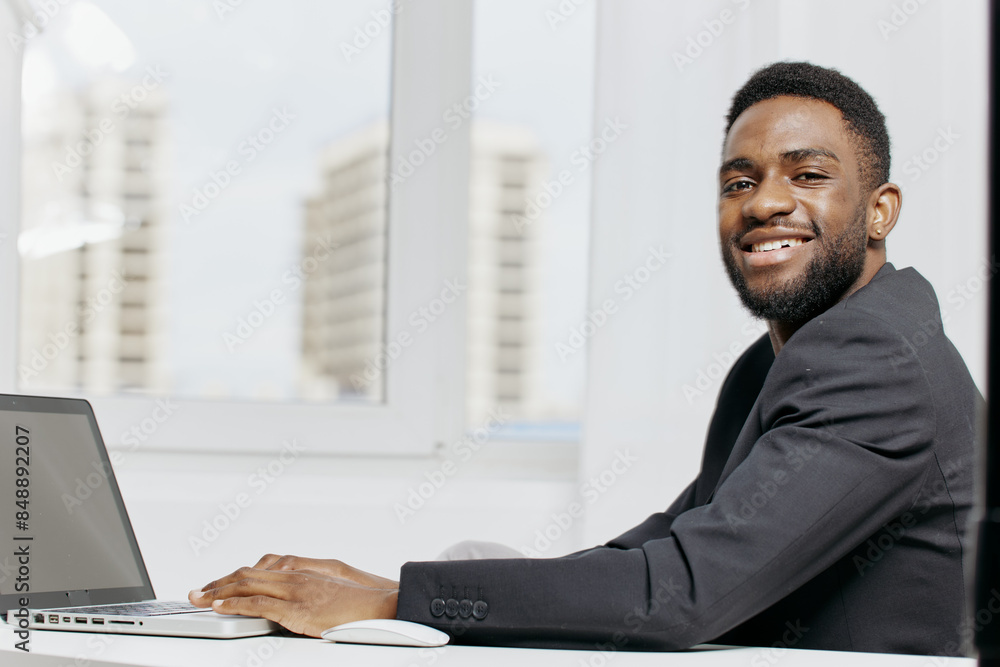 African american businessman seated at desk working on laptop in professional office environment African american businessman seated at desk working on laptop in professional office environment
